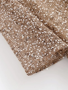 Macro detail of silver sequins on bronze mesh fabric for a shimmering fashion dress
