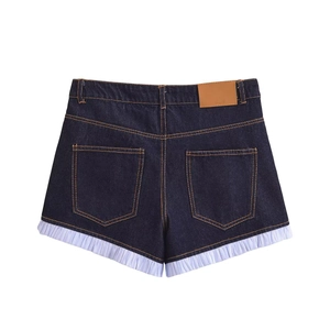 Detail of dark blue denim shorts with purple ruffled hem and brown leather patch