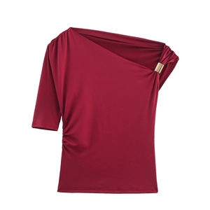Détail du haut asymétrique rouge vin avec boucle dorée et plis élégants sur l'épaule