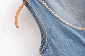 Gros plan détaillé du tissu denim bleu clair avec bordure en dentelle blanche et coutures