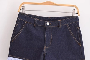 Detail of dark blue denim shorts with orange stitching and stylish striped trim