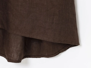 Détail d'une robe trapèze en lin marron foncé avec ourlet arrondi et couture précise
