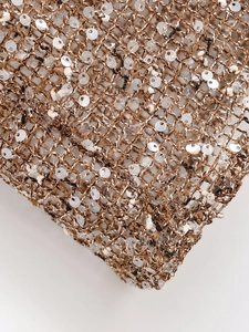Detailed close-up of brown knit mesh fabric with decorative silver sequins on dress
