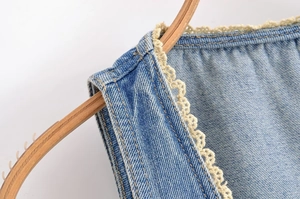 Détail macro du tissu denim bleu clair avec bordure délicate en dentelle crochetée crème