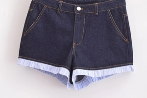 Detail of dark blue denim shorts featuring striped ruffle trim and yellow contrast stitching