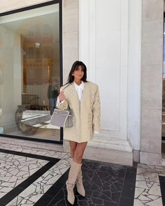 Detailansicht eines beigen Oversize-Blazers mit silbernen Nieten und Web-Handtasche