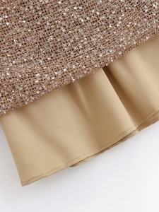 Detail of sequin mesh fabric with gold texture and soft khaki lining on dress hem