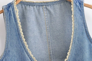 Détail de l'encolure en denim bleu avec bordure en dentelle blanche et surpiqûres jaunes