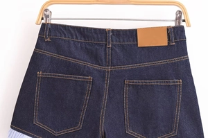 Detail of high waist denim shorts with back pockets and light blue pleated hem patchwork