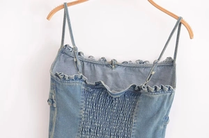 Dettaglio di canotta in denim blu con scollo a balze e design elastico arricciato sul retro