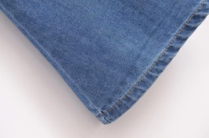 Détail de la double couture jaune et de la finition de l'ourlet en denim bleu