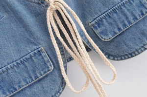 Détail du haut en jean bleu avec taille à cordon et poches à rabat en denim délavé