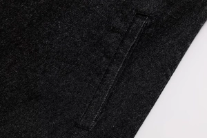 Detailed macro view of black denim fabric with precise welt pocket stitching and texture