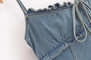 Dettaglio del top in denim con scollo a balze, coulisse regolabile e cuciture a contrasto