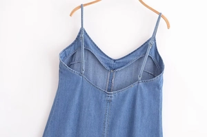Détail d'une robe en jean bleue avec bretelles réglables et coutures apparentes nettes