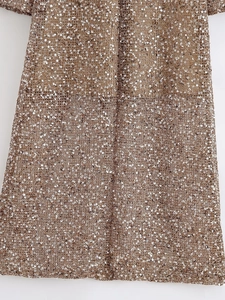 Detailed macro shot of shimmering champagne gold sequins on an elegant party dress fabric