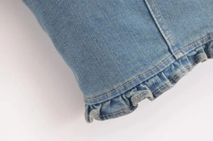Dettaglio di bordi a volant e doppia cucitura gialla su top in denim azzurro
