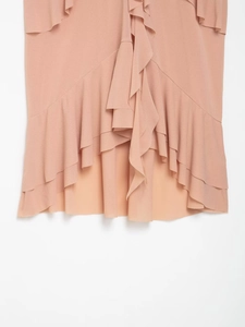 Close-up of elegant ruffled layers and textured fabric on a peach sleeveless top