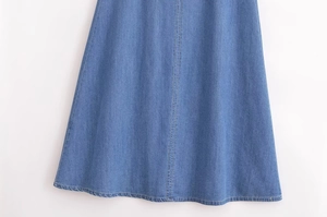 Détail de l'ourlet de la jupe en jean bleu montrant les coutures et le tissu délavé