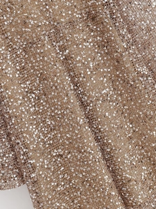 Macro detail of champagne gold sequin mesh fabric with metallic pearlescent luster