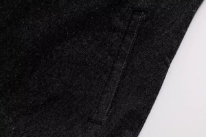 Close-up of black denim fabric texture and diagonal pocket stitching on dress