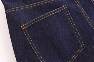 Detailed close-up of dark blue denim rear pocket with classic orange contrast stitching