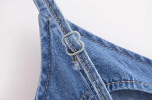 Gros plan détaillé de la bretelle de robe en jean bleu avec boucle de réglage grise
