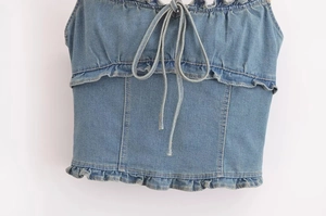 Dettaglio di volant a strati e lacci su un top a fascia in denim lavato da donna