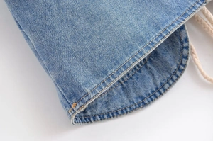 Détail de l'ourlet en denim bleu clair avec coutures tabac et cordon de serrage blanc tressé