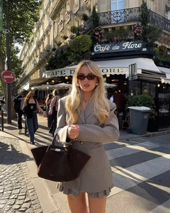Dettaglio dell'abito blazer pied de poule con cintura davanti a un caffè di Parigi