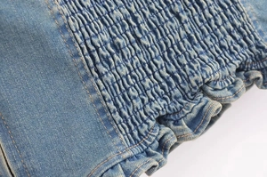 Dettaglio macro della lavorazione a punto smock e volant su top in denim lavato blu