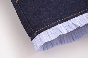 Detail of dark denim hem with light blue striped ruffle and orange contrast stitching