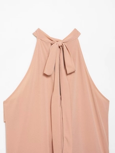 Close-up of a peach halter neck top featuring a back bow tie and soft textured fabric