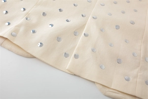 Detailansicht eines beigen Blazers mit polierten silbernen Metallnieten-Verzierungen