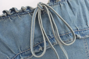 Dettaglio del top in denim con bordo a volant, coulisse e cuciture gialle a contrasto