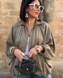 Detailaufnahme der Puffärmel einer olivgrünen Bomberjacke mit modischen Accessoires