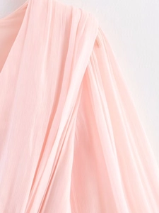 Detail of light pink chiffon dress showing fine pleated texture and soft flowing fabric