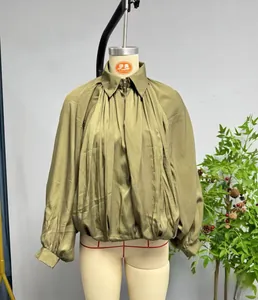 Detail of dark green oversized jacket featuring pleated fabric texture and zipper closure