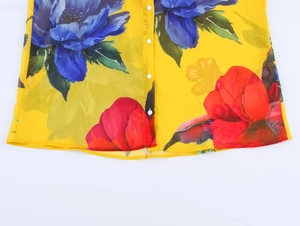 Detailansicht der gelben, transparenten Blumenbluse mit blauen und roten Blütenmustern