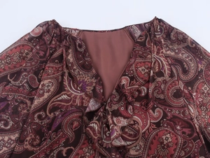 Detail of V-neckline with ruffles and burgundy paisley print on chiffon fabric