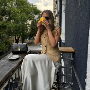 Damen Sommeroutfit mit khakifarbener Leinenweste und einem weißen Satin-Maxirock