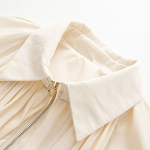 Detailaufnahme von Metallreißverschluss und Rippenstruktur der cremeweißen Jacke