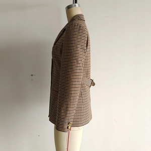 Dettaglio del blazer pied-de-poule con bottoni dorati e cintura posteriore regolabile