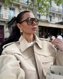 Close-up of off-white suede biker jacket with gold earrings and dark sunglasses
