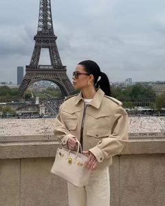 Detail of beige faux suede jacket with shoulder tabs and flap pockets in a city setting