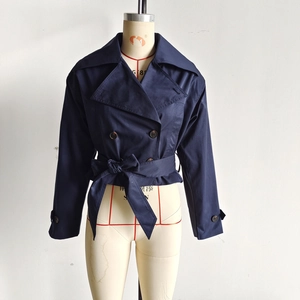 Close-up of navy blue double-breasted cropped trench jacket with waist tie and large lapels