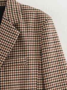 Dettaglio del rever e della tasca di un blazer pied-de-poule nei toni marrone e beige
