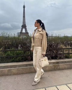 Detail view of a khaki suede cropped jacket styled with high-waist trousers in Paris