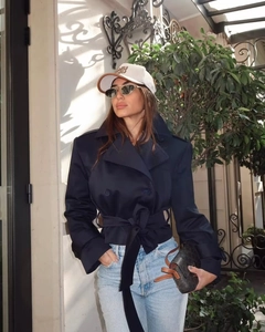 Detail of navy blue double-breasted trench coat with waist belt and lapel collar