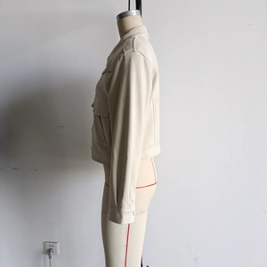 Detailed view of beige suede jacket showing shoulder epaulets and large flap pockets
